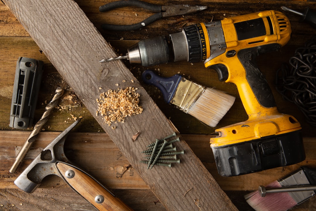 A cordless drill and other tools laid out on a wooden workbench