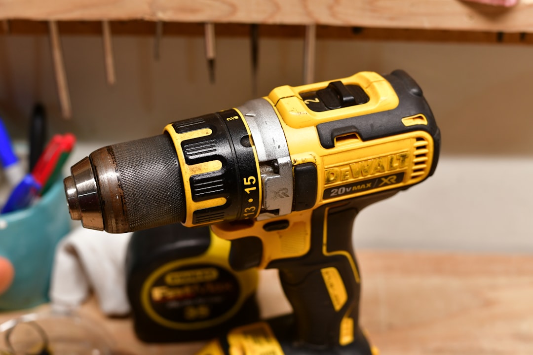 A yellow and black cordless drill on a wooden workbench