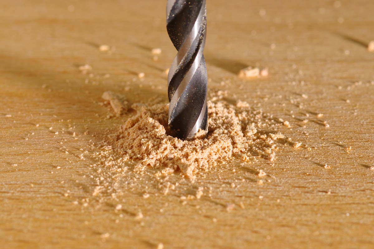 Cordless hammer drill drilling into a wooden board in a UK workshop