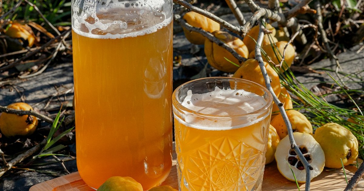 Bottle of apple cider next to a glass of golden cider