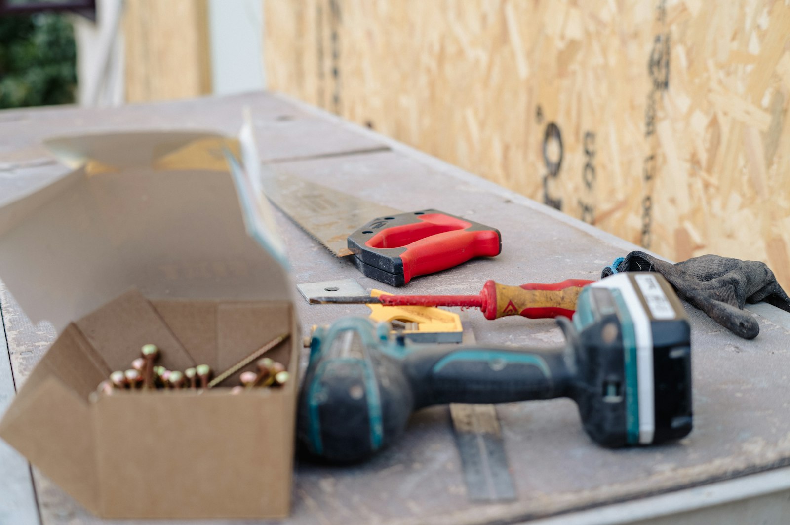 Cordless drill and hand tools laid out on a wooden workbench