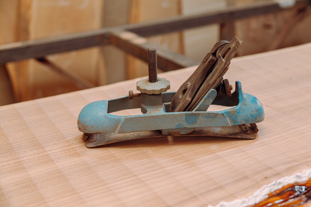 Old cast iron jointer plane resting on a wooden workbench surrounded by woodworking tools