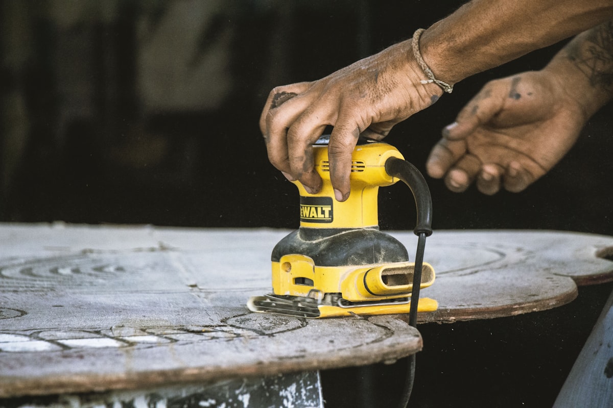 Random orbital sander on a wooden workbench with sawdust and sanding discs