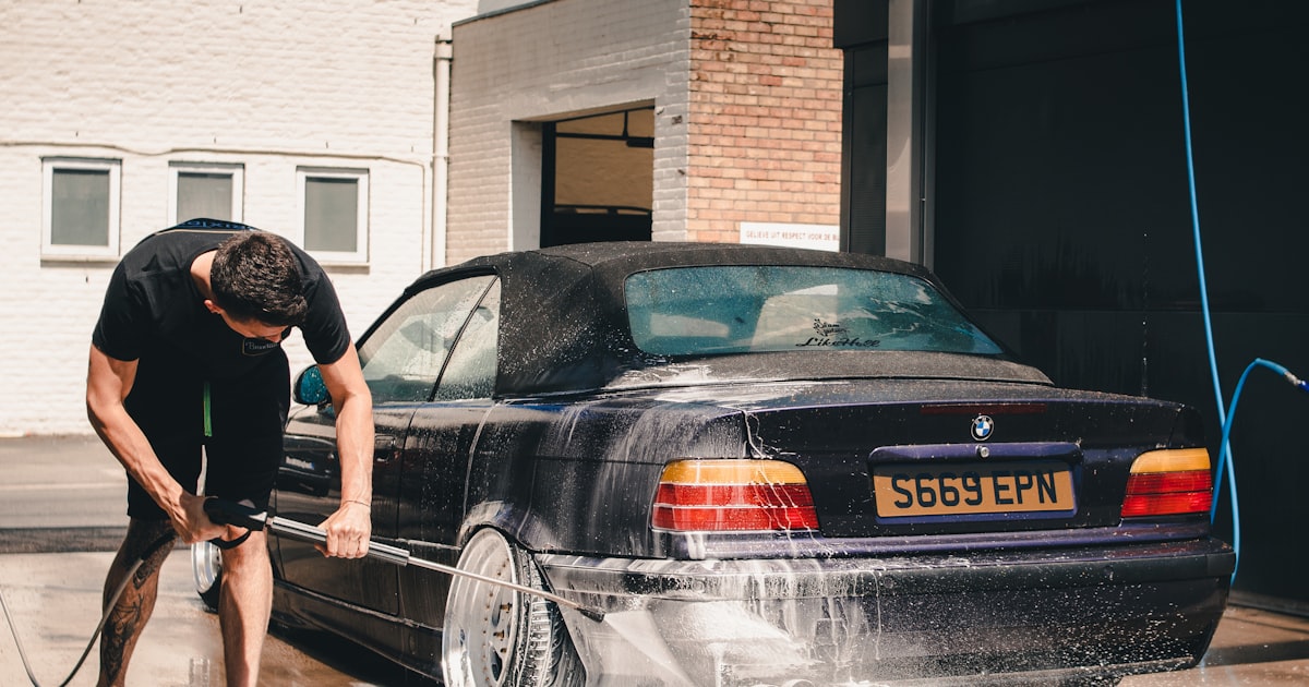 Person washing a car with a pressure washer before applying ceramic coating or wax