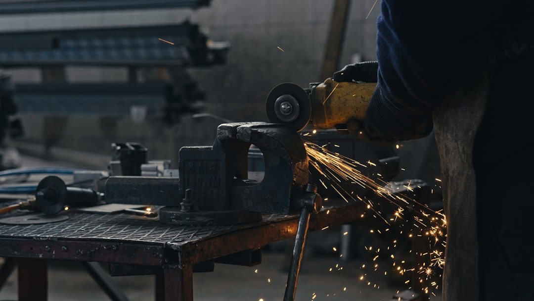 Worker using an angle grinder on a metal bar with bright sparks flying