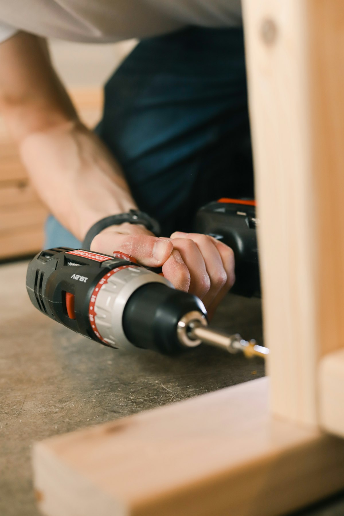 Cordless drill with accessories and drill bits laid out on a workshop bench