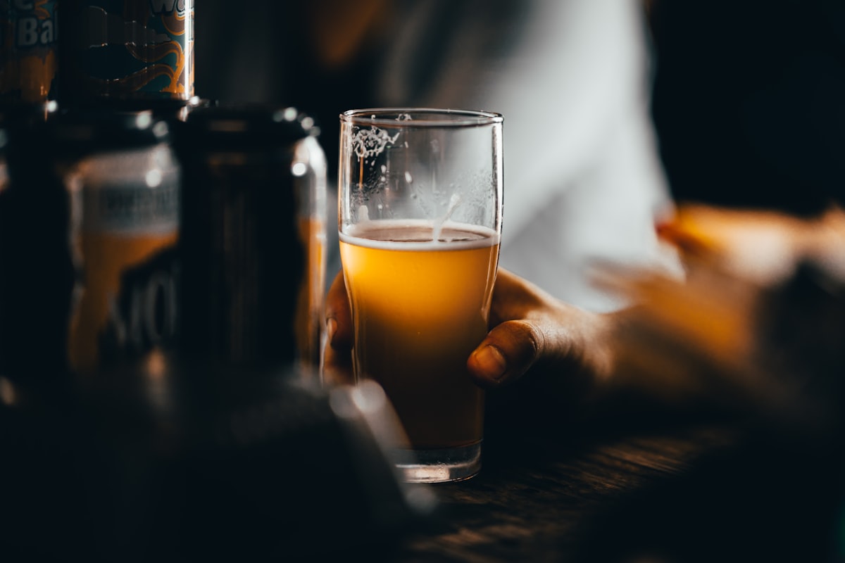Home brewing equipment with a fermenter, beer bottles and brewing ingredients on a wooden table