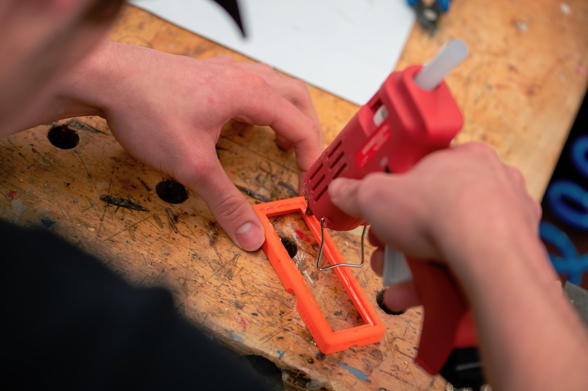 Hot glue gun and glue sticks on a craft workspace table
